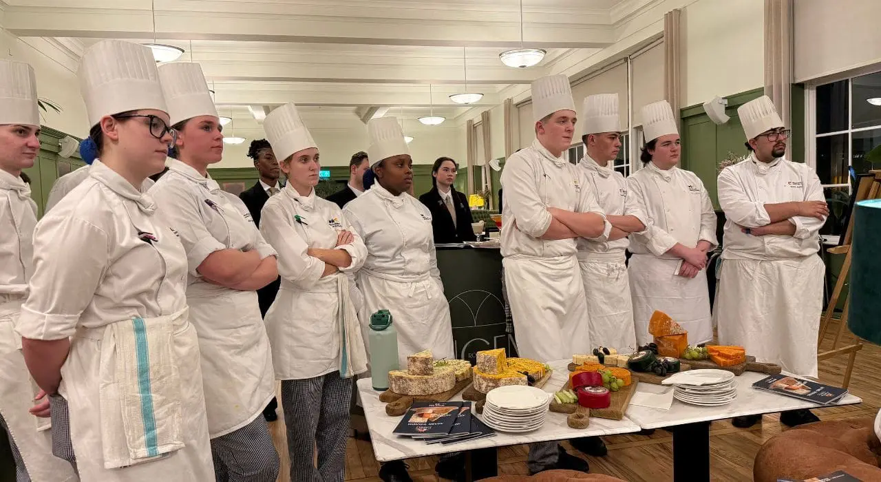 Group of student chefs standing in front of a table filled with cheese