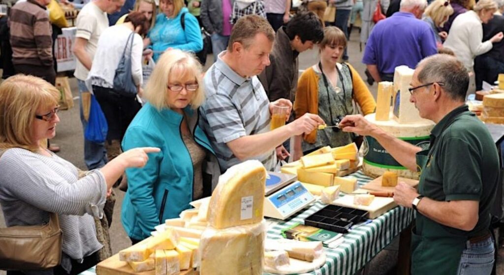 Visitors to Artisan Cheese Fair in Melton Mowbray looking at cheese stall and tasting cheese