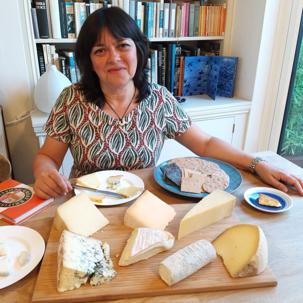 Jenny Linford sitting in front of a board of a selection of cheeses