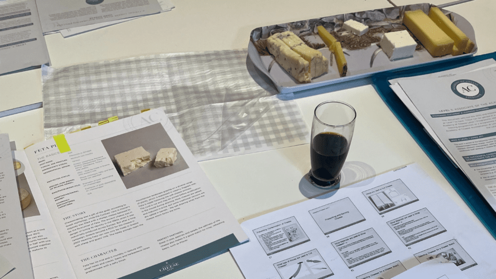 Academy of Cheese Study Materials including 25 cheeses book and a plate of cheeses including Stilton, Gruyere and Feta